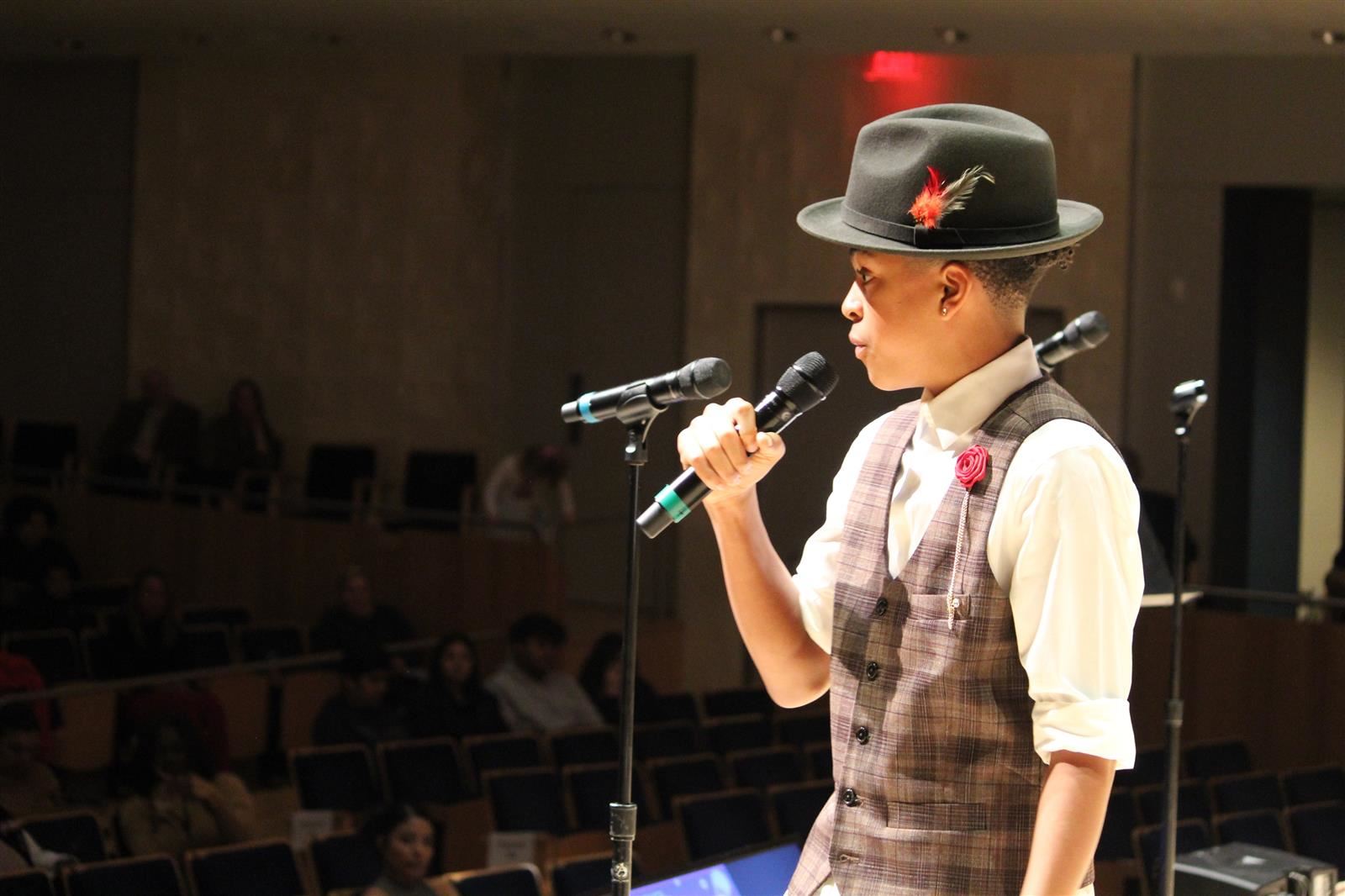  boy sings into microphone on stage